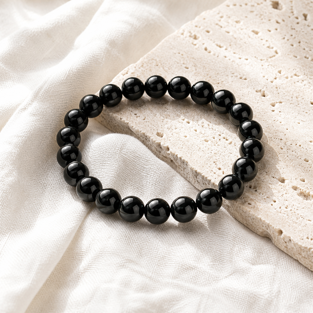 Black Obsidian bracelet on pale travertine stone and off-white linen