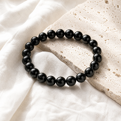 Black Obsidian bracelet on pale travertine stone and off-white linen